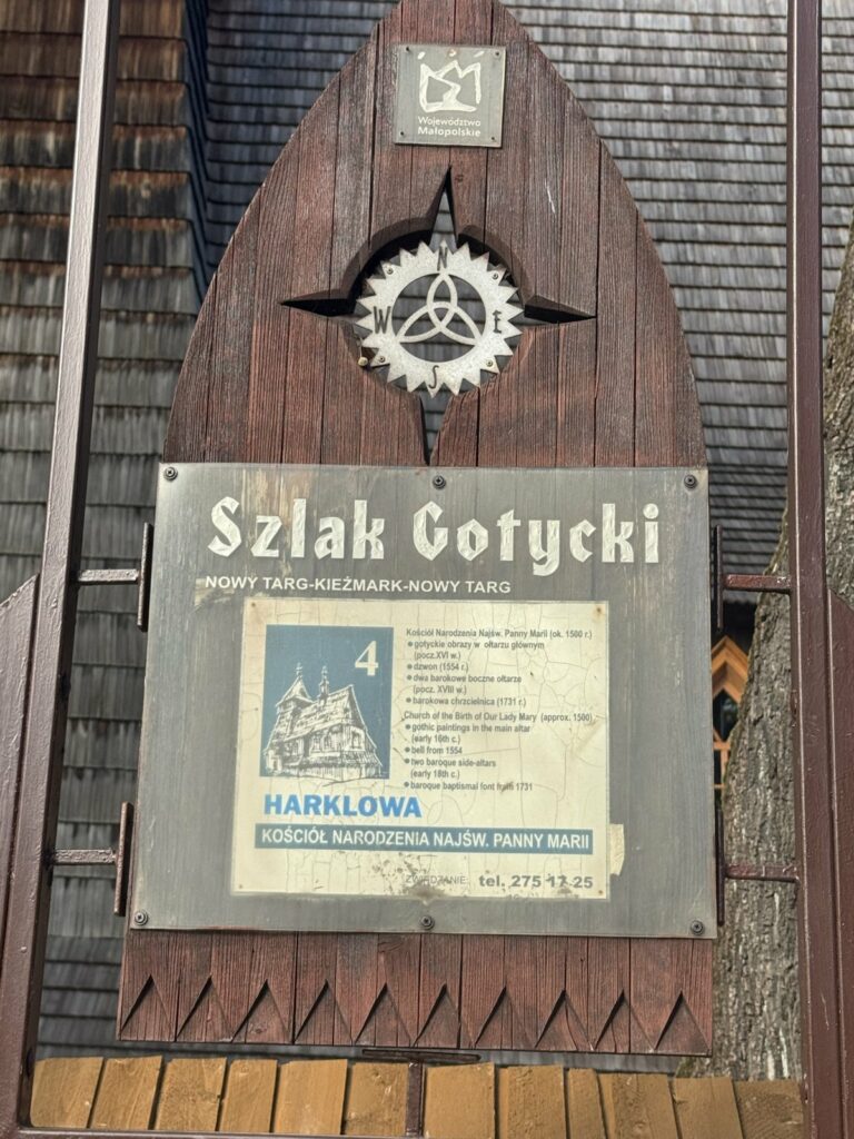 Tabliczka Szlaku Gotyckiego (Nowy Targ – Kieżmark – Nowy Targ) przy kościele w Harklowej